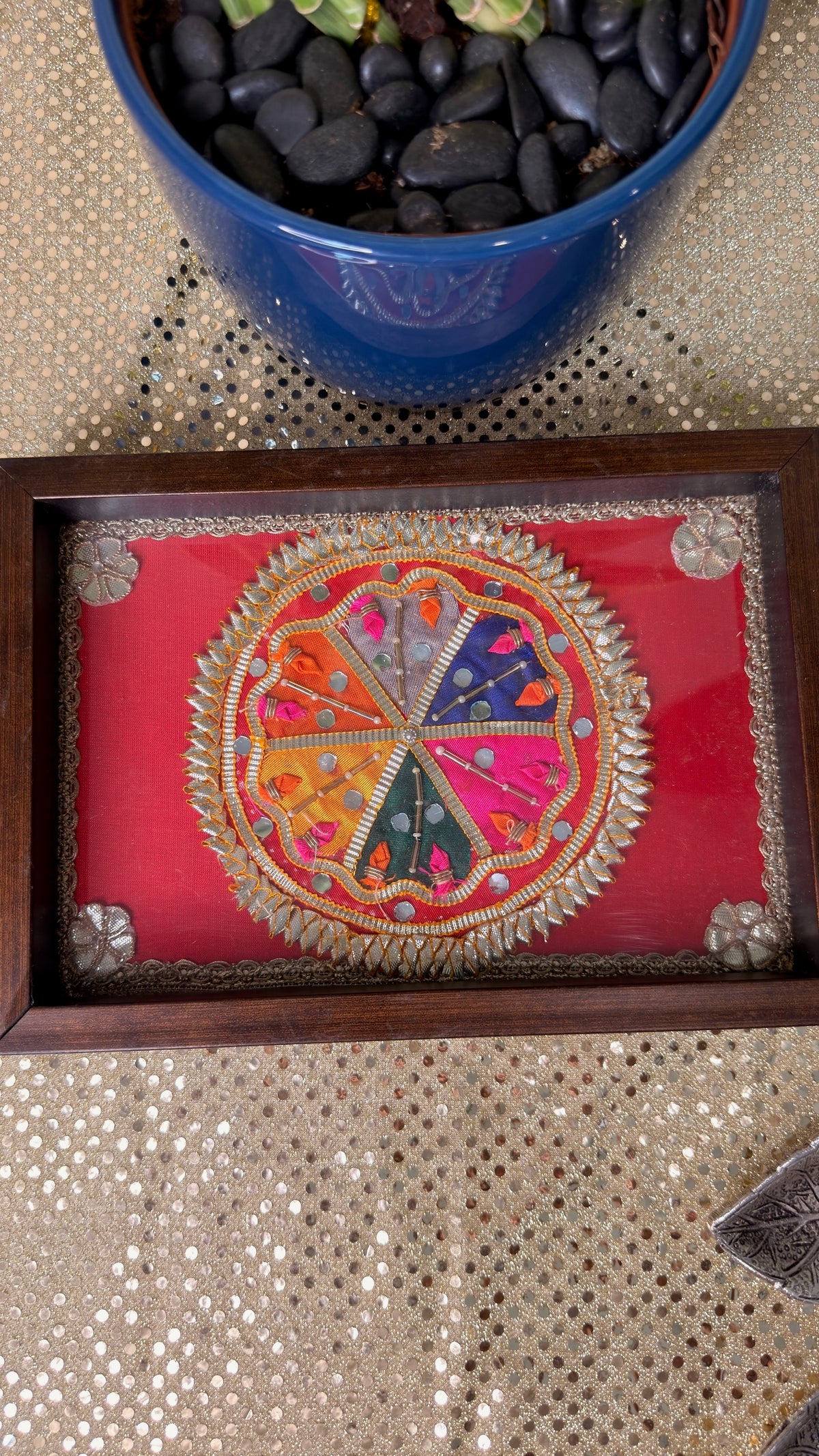 Top view of red silk embroidered mandala under glass on wooden tray