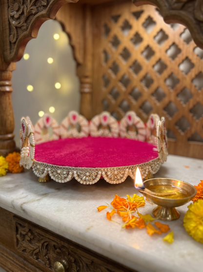 Magenta velvet round puja thali with pearl kundan scalloped rim, front view in a festive mandir setting