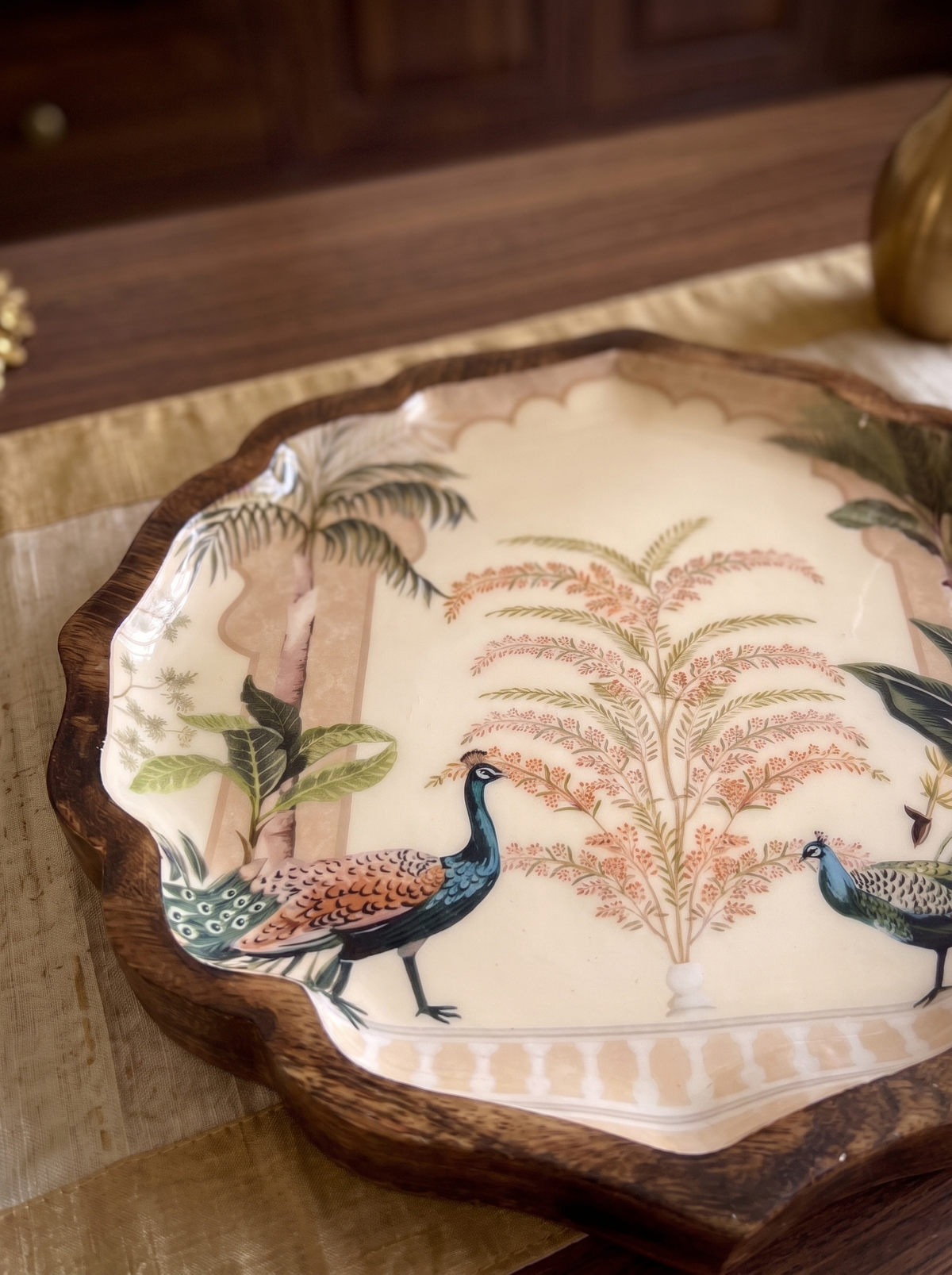Close-up detail of peacock and palm garden print on scalloped wooden platter