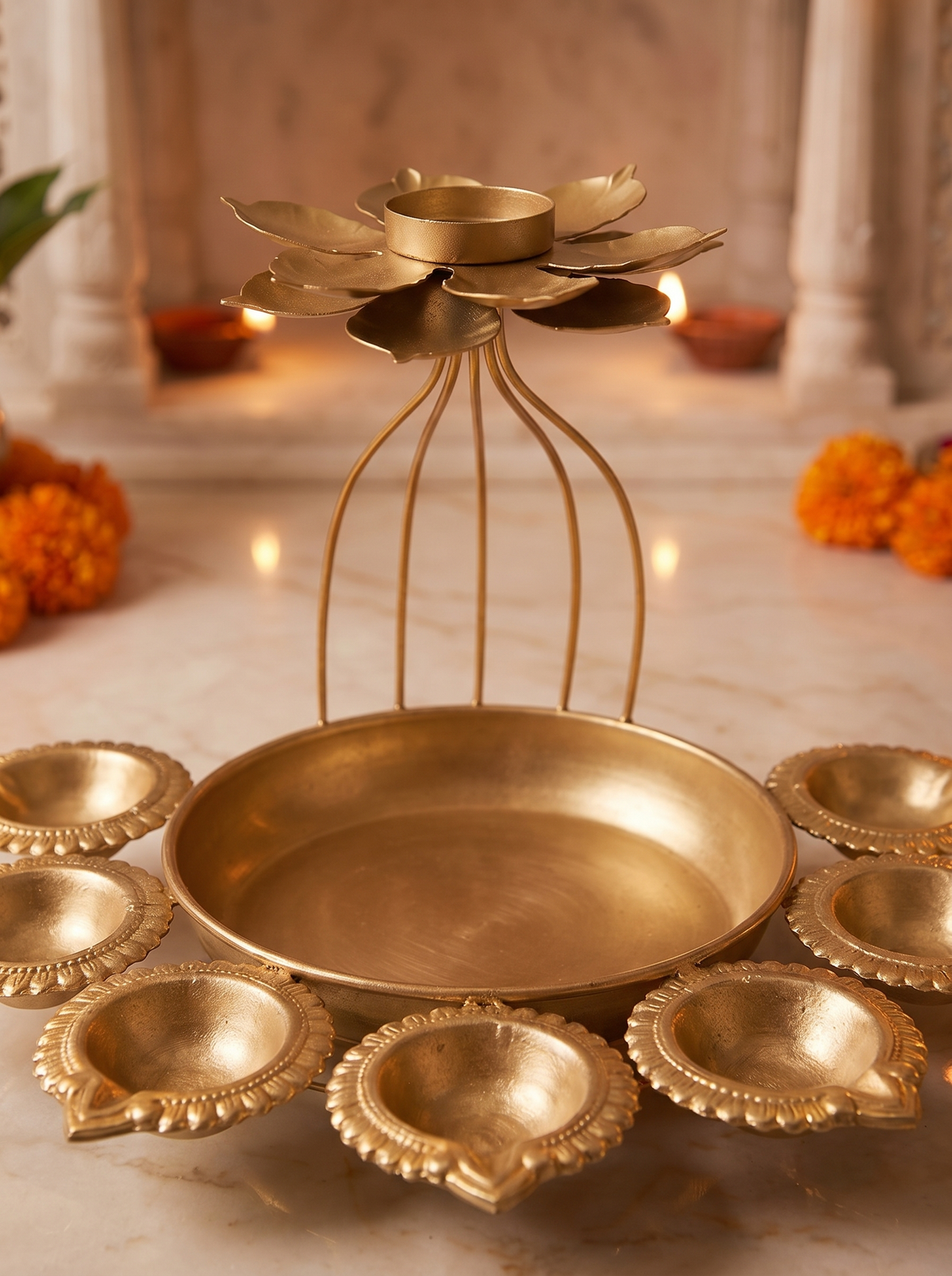 Close-up detail of hammered gold bowl and wire-cage lotus on Diwali diya set