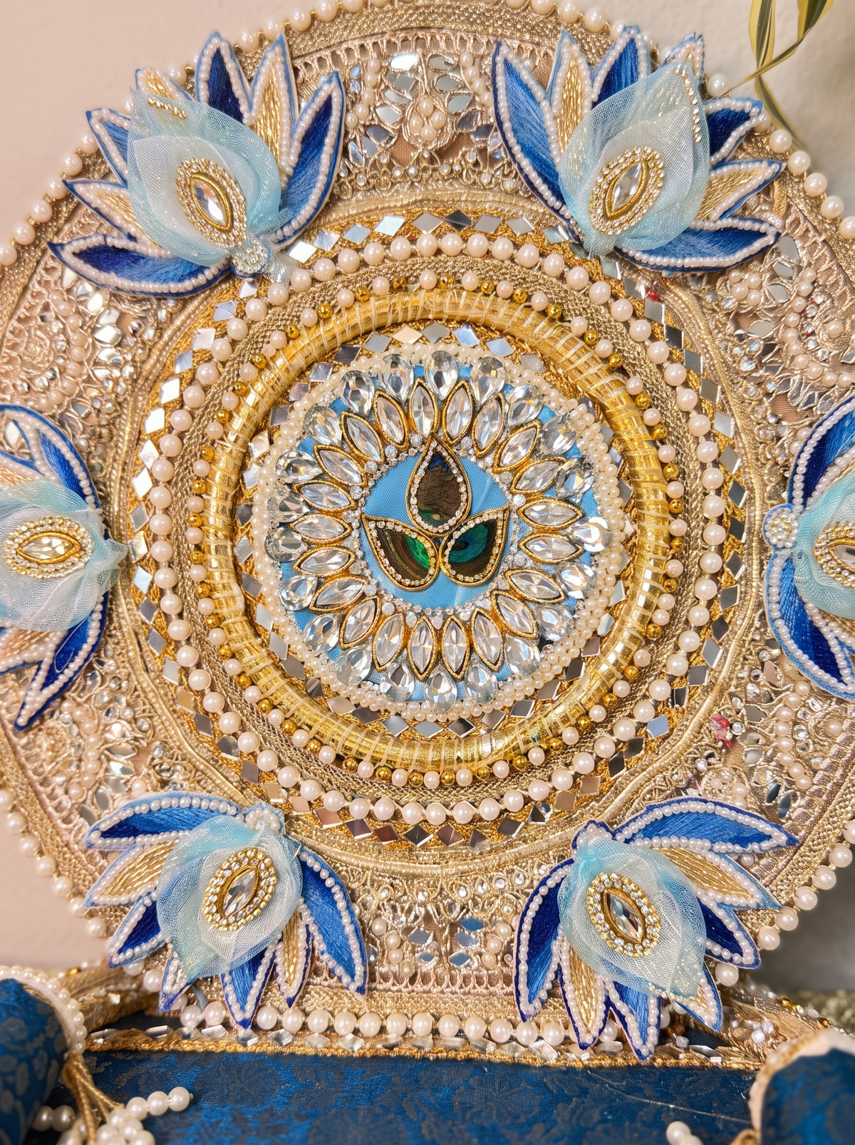 Close-up detail of silver zari embroidery and pearl trim on blue lotus Laddu Gopal singhasan