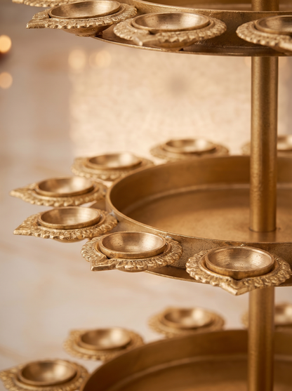 Close-up detail of lotus diya cups and kalash finial on gold 3-tier tealight stand