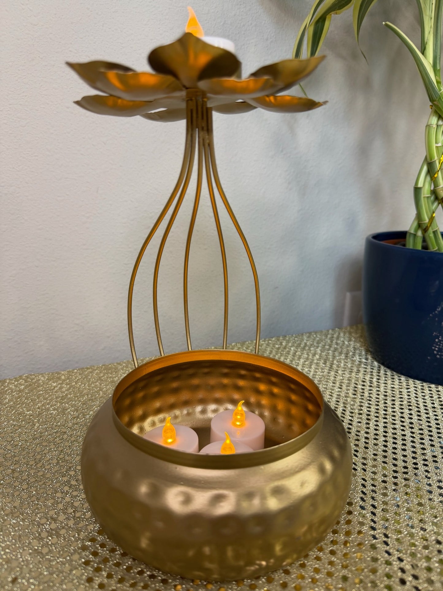 Gold wire-cage urli with tealights inside, angled view
