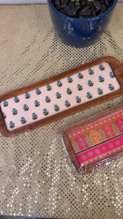 Blue floral wooden serving board beside pink brocade print board, Diwali cheese platter