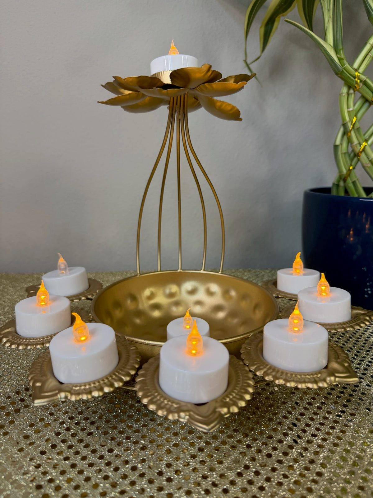 Gold wire-cage diya set with lit tealights, angled view on festive cloth