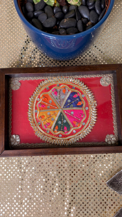 Top view of red silk embroidered mandala under glass on wooden tray