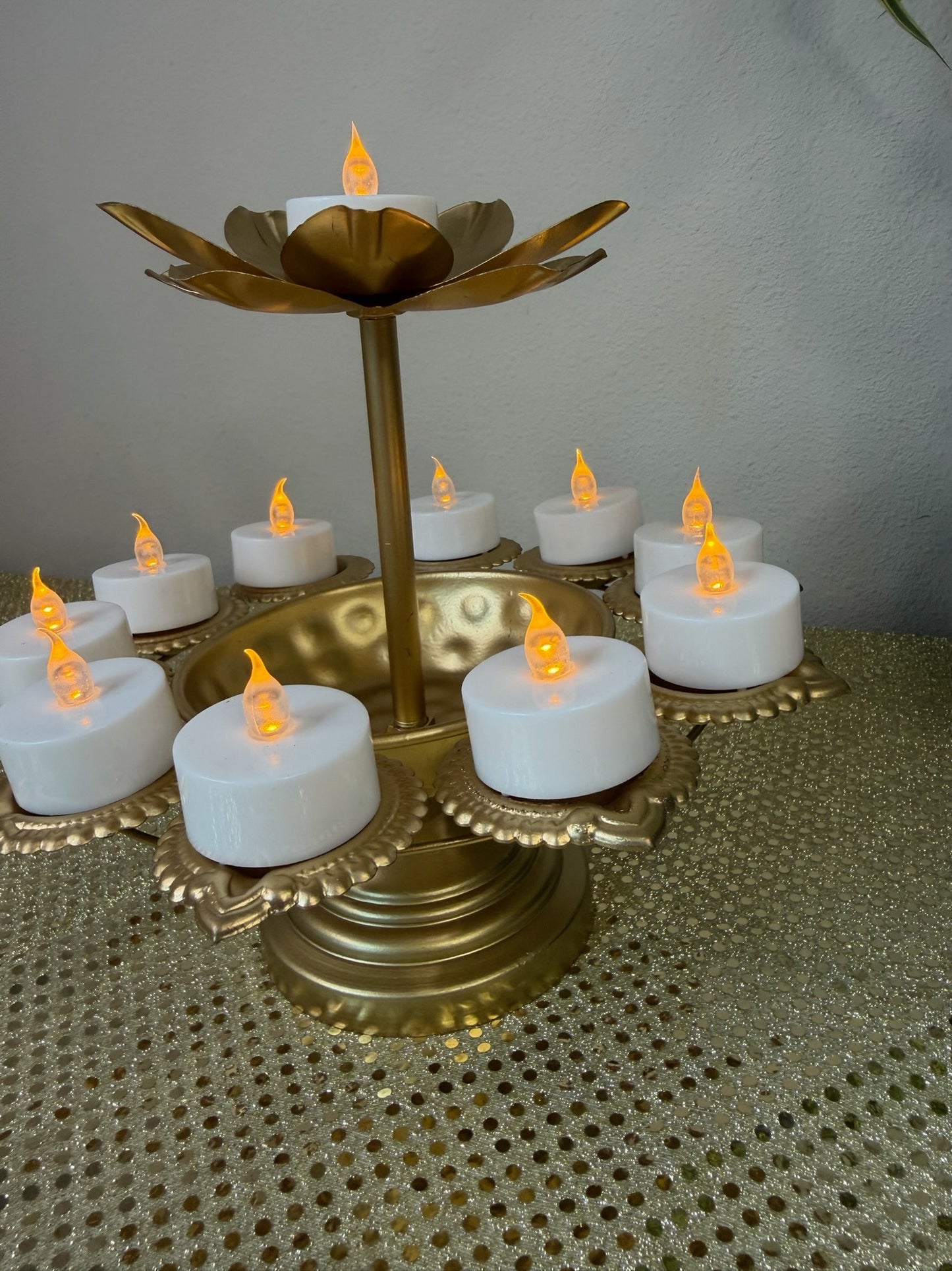 Gold pedestal diya stand with eight tealight cups, angled view