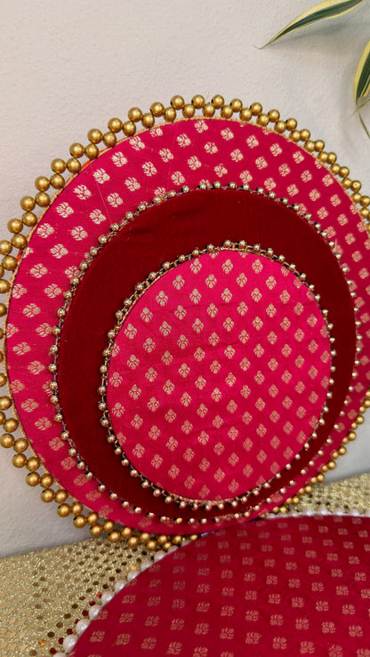 Close-up of pink brocade nested thalis with gold bead rims