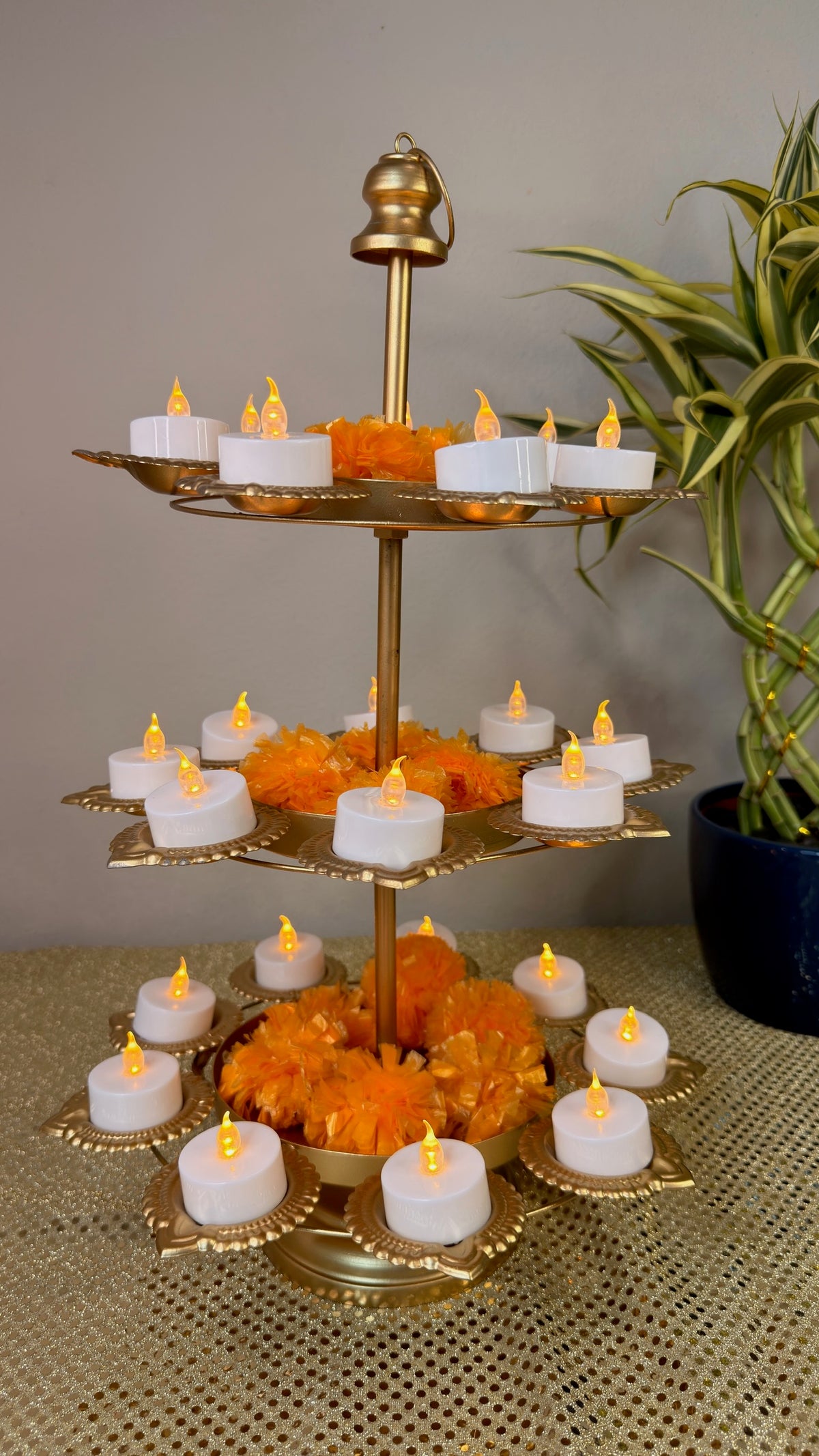 Three-tier gold lotus diya tower decorated with marigolds and tealight candles