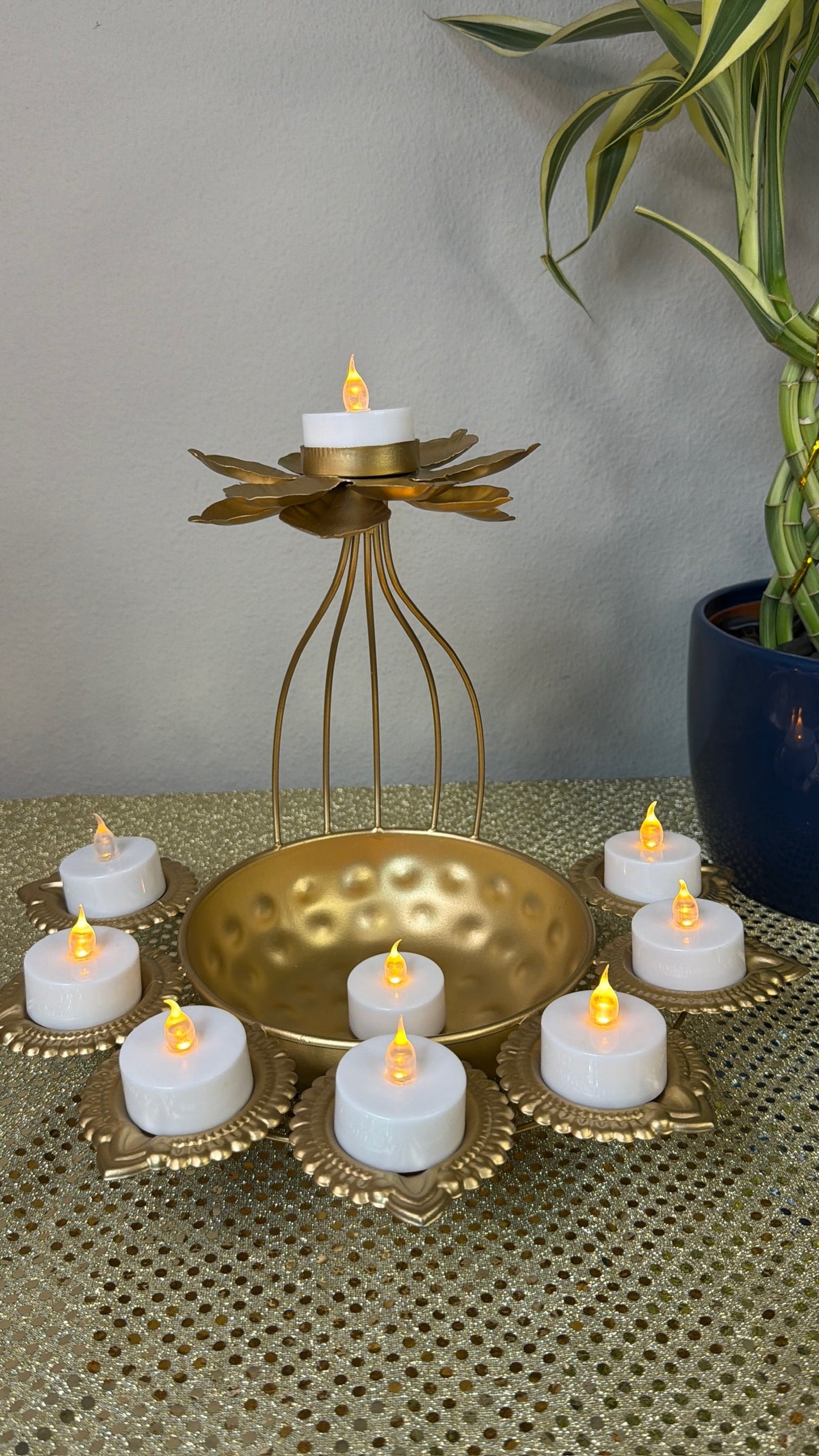 Lit tealights in gold lotus diya cups around wire-cage bowl centerpiece