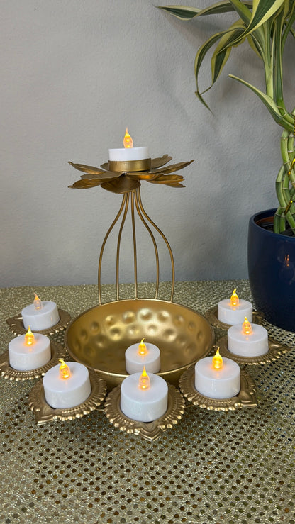 Lit tealights in gold lotus diya cups around wire-cage bowl centerpiece