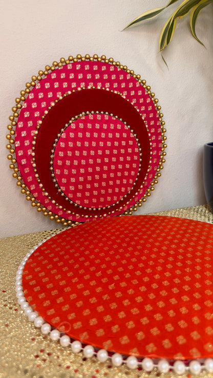 Pink brocade nested thalis stacked on orange brocade mat, Indian festive tray set