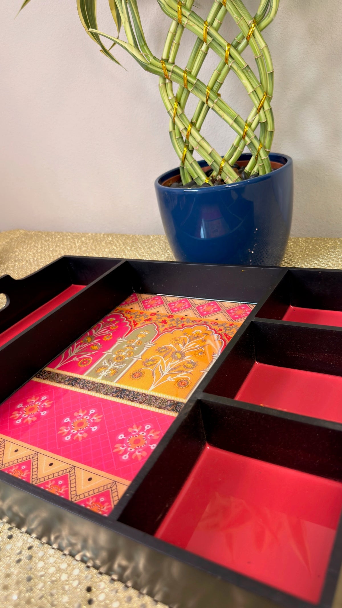 Close-up of pink and orange brocade panels in black lacquer sectioned tray