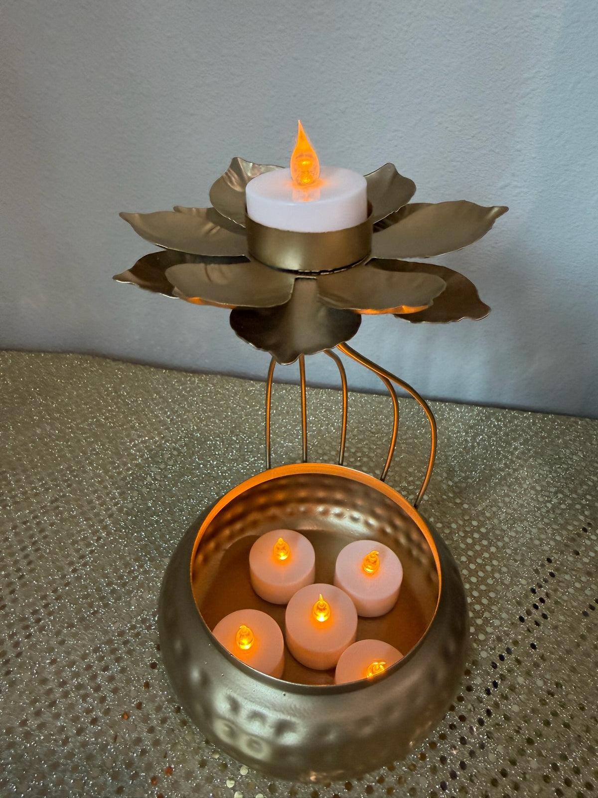 Close-up of lotus tealight cup on gold hammered urli pot