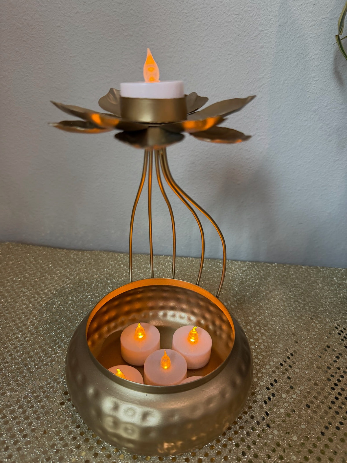 Gold hammered urli diya with lit lotus tealight on top