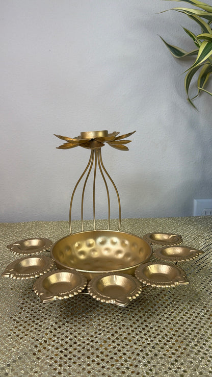 Gold hammered urli bowl with seven lotus diya cups arranged around it