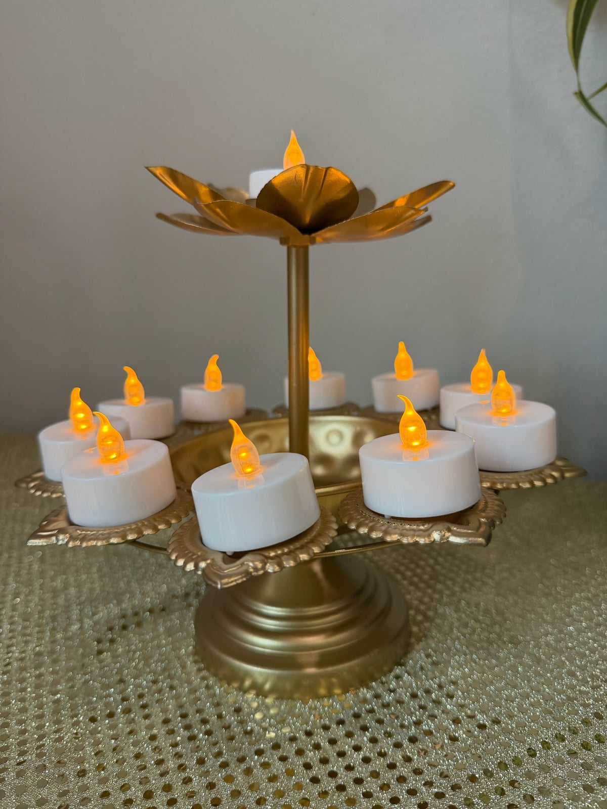 Gold pedestal lotus diya stand with lit tealight candles