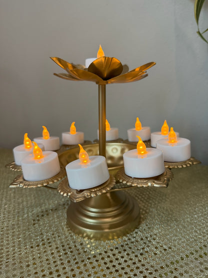 Gold pedestal lotus diya stand with lit tealight candles