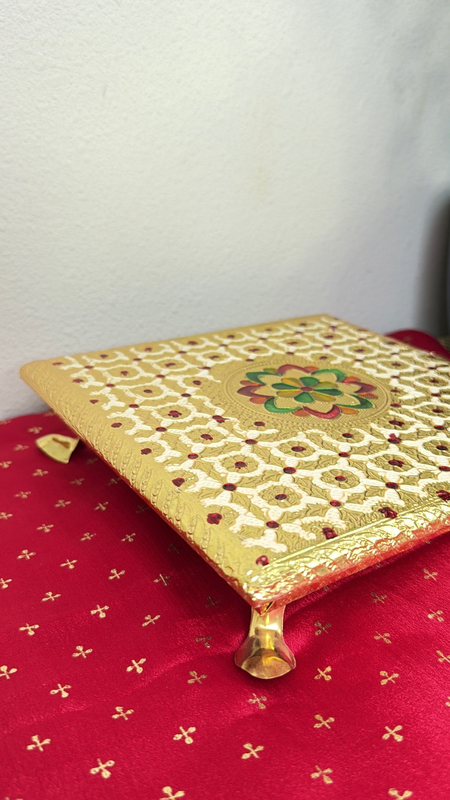 Gold brocade square bajot chowki for idol placement, angled view